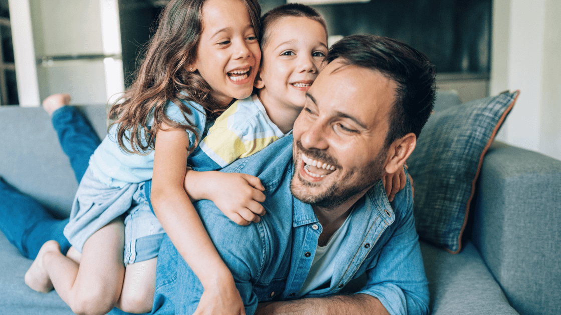 Happy father spending quality time with two children on the couch during holiday season