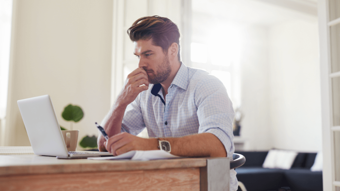 A man sits at a desk, thoughtfully focused on his laptop, reflecting the process of deciding if mediation is the right choice.