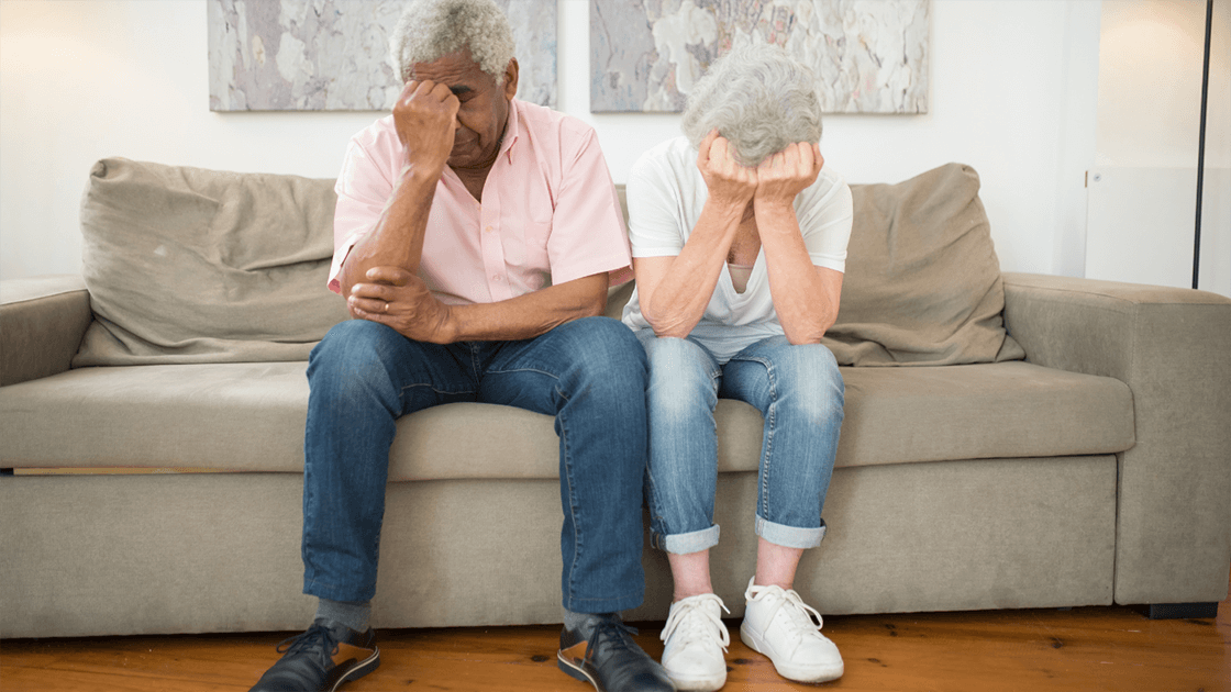 An older couple sitting apart in deep thought, representing the emotional and financial challenges of gray divorce.