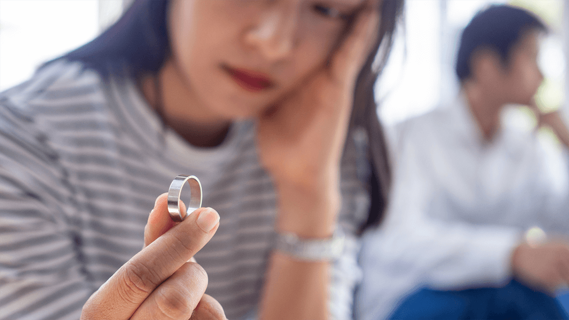 A woman staring at her wedding ring considering what it will be like to schedule a family law consultation as her next step to getting divorce.