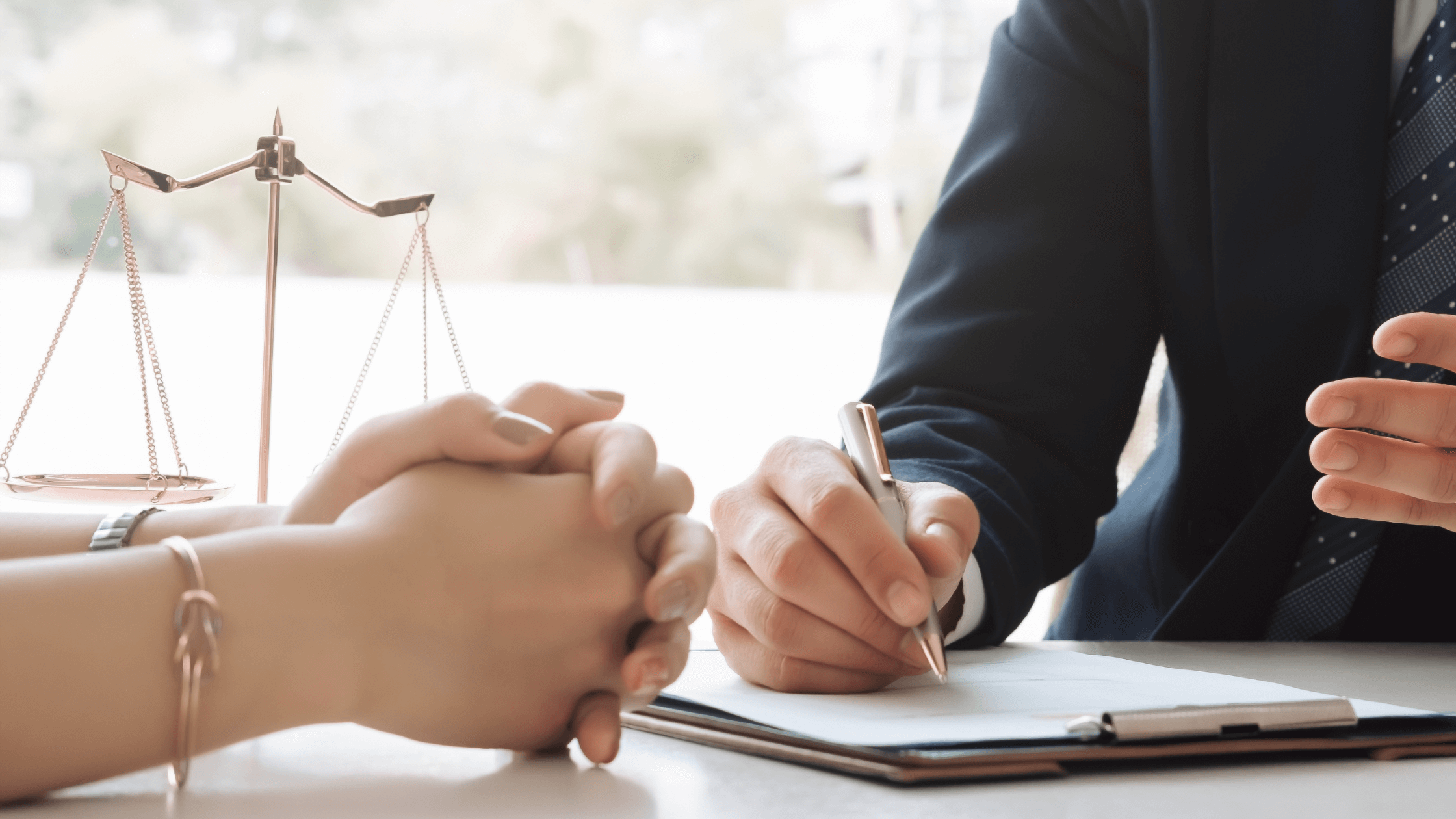 Hands clasped across a table from a lawyer writing, symbolizing a divorce attorney consultation texas and the first meeting with divorce lawyer texas to discuss divorce.
