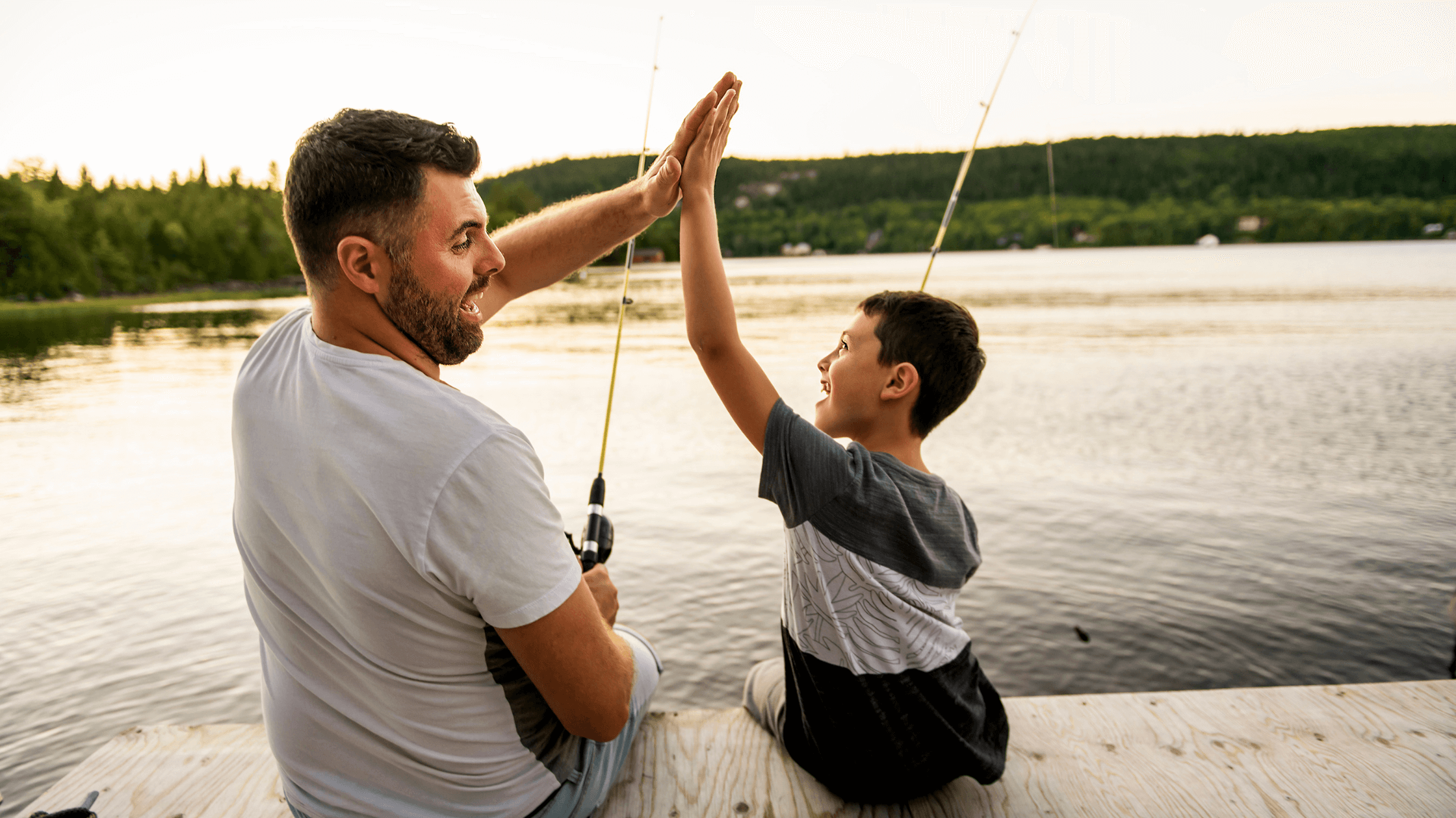 A father and son high-five while fishing on a dock, symbolizing positive co-parenting and child well-being, relevant to Texas 50 50 custody discussions and Texas child custody laws.
